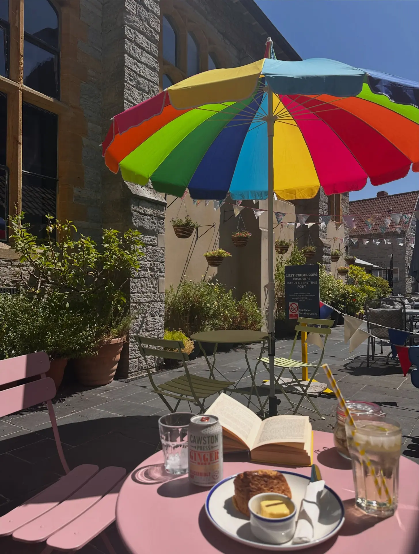 Café tables with a rainbow parasol in the sunny Crispin Hall courtyard